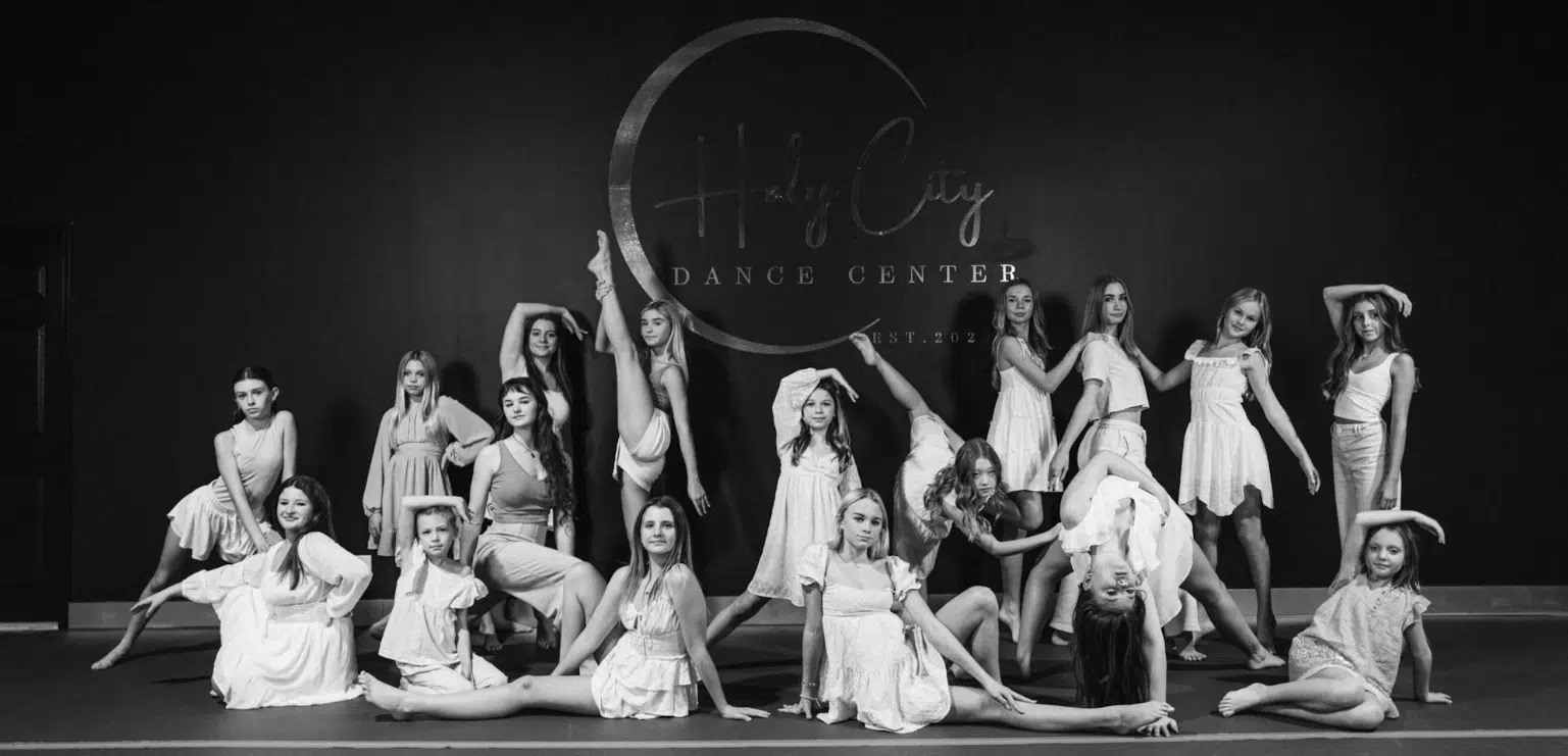 Holy City Dance Center dancers posed around the Holy City Dance logo in white dresses in various dancing positions.
