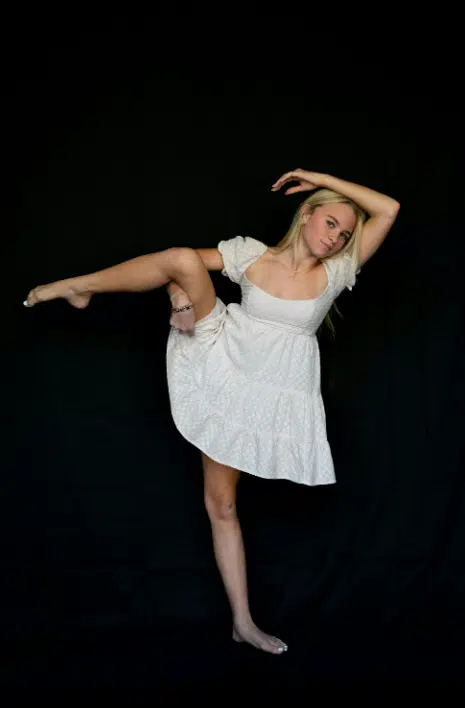 Blonde girl wearing a white dress in a dance position