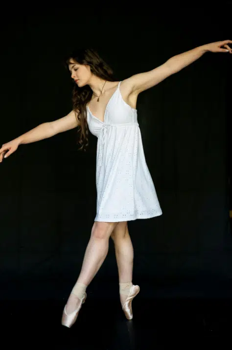 Brunette ballet dance for Holy City Dance Center on her tiptoes with her arms in a T position